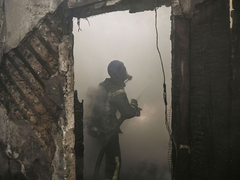 Firefighters extinguish a burning house hit by Russian Grad rockets in Kyiv's Shevchenkivsky district, on March 23, 2023. 