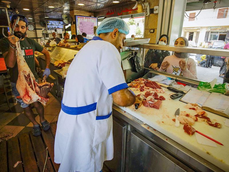 This file photo taken on July 28, 2020 shows people waiting for their orders at a butcher shop Tripoli. Lebanon used to import 70 containers of frozen meat every month, but now the number is nearly 40. 