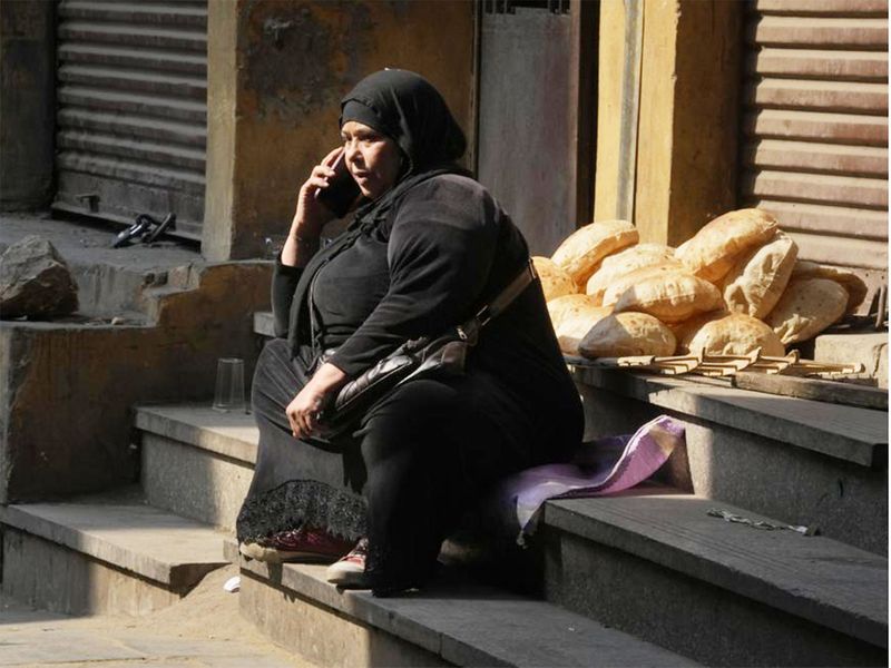 A vendor makes a mobile call as she waits for clients to sell Egyptian traditional 