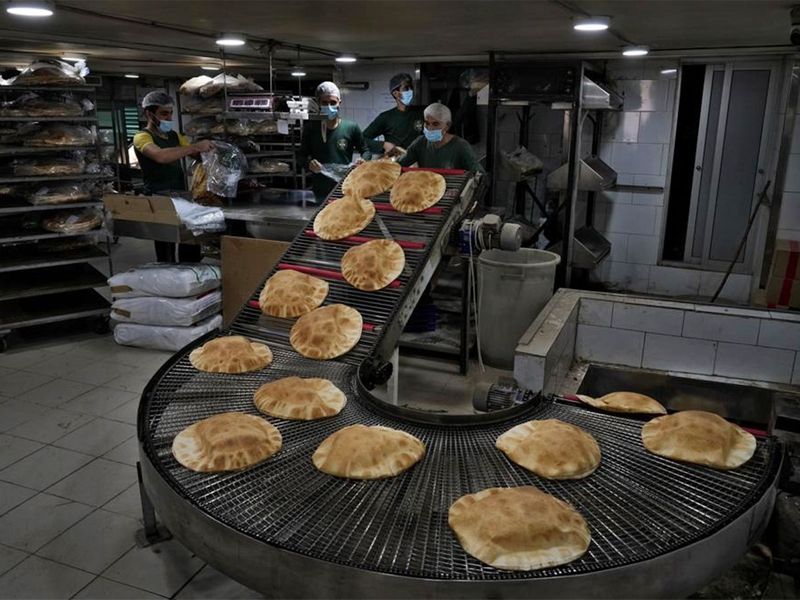 Bakery workers package freshly-produced bread coming off a production line at an automated bakery in the southern Beirut suburb of Dahiyeh, Lebanon. 