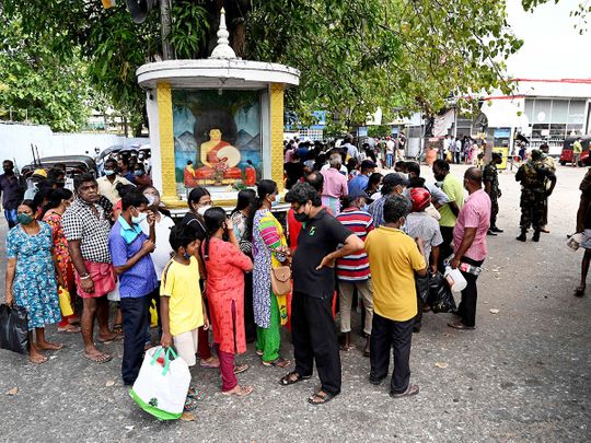 People stand in a queue to buy kerosene for home use at a service station in Colombo.  