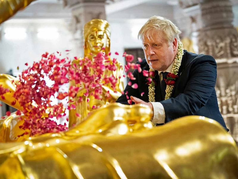 British Prime Minister Boris Johnson scatters rose petals during his visit at the Swaminarayan Akshardham temple in Gandhinagar, Ahmedabad. 