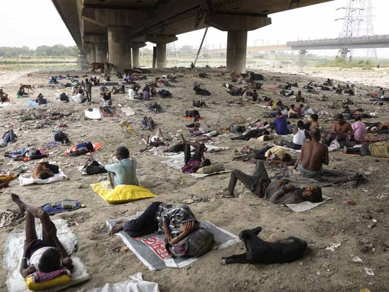 Homeless people sleep in the shade of an overbridge on a hot day in New Delhi, India.