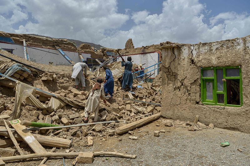 Afghan men look for their belongings amid the ruins of a house damaged by an earthquake in Bernal district, Paktika province, on June 23, 2022. - Desperate rescuers battled against the clock and heavy rain on June 23 to reach cut-off areas in eastern Afghanistan after a powerful earthquake killed at least 1,000 people and left thousands more homeless