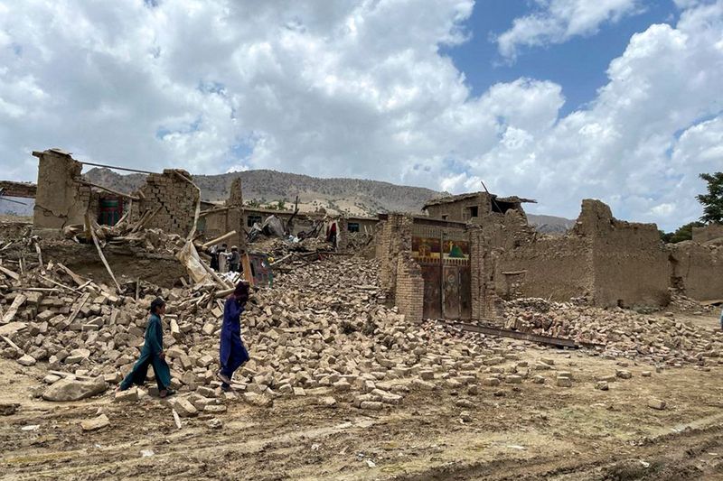 People walk amidst the rubble of damaged houses following a 5.9-magnitude earthquake in Bermal district, Paktika province, on June 23, 2022. -