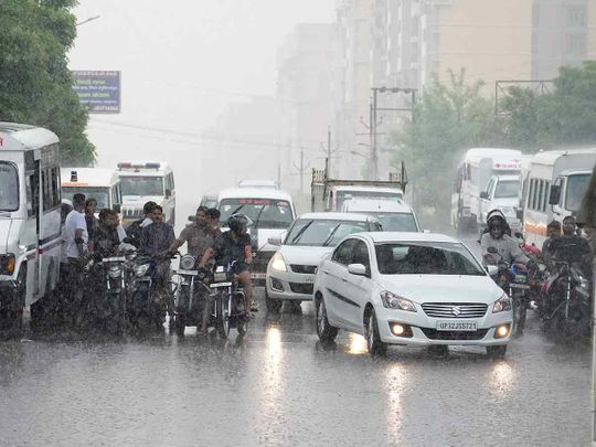 People wait at a turn as it rains in Lucknow, in the northern Indian state of Uttar Pradesh, on Saturday, July 2, 2022. India's monsoon season runs from June to September. 