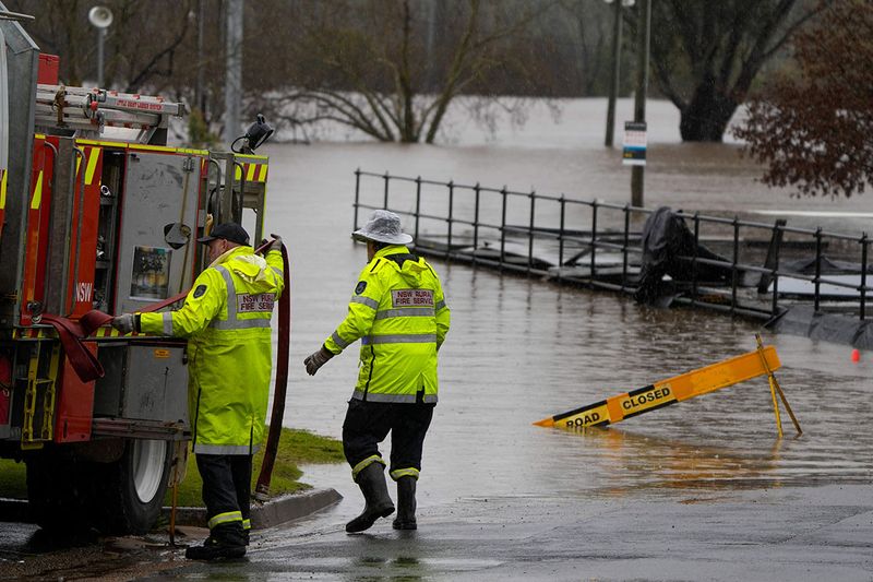 Members of local fire brigade work at a flooded sports venue in Camden on the outskirts of Sydney, Australia, Monday, July 4, 2022. More than 30,000 residents of Sydney and its surrounds have been told to evacuate or prepare to abandon their homes on Monday as Australia’s largest city braces for what could be its worst flooding in 18 months. 