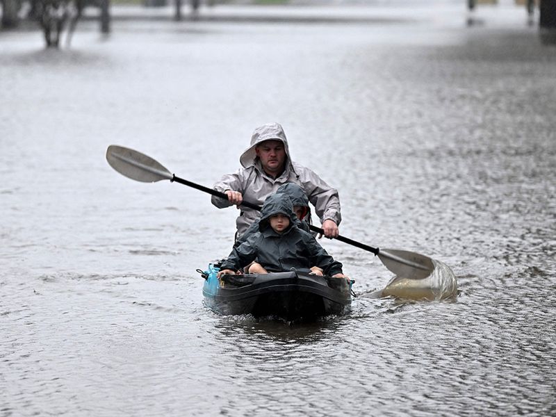 People kayak along a flooded street from the overflowing Hawkesbury river due to torrential rain in the Windsor suburb of Sydney on July 4, 2022. 