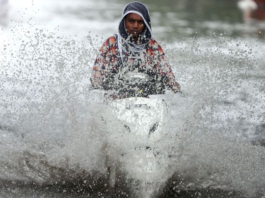 A person rides a scooter through a waterlogged road during monsoon rain showers in Mumbai, India, June 4, 2020. 