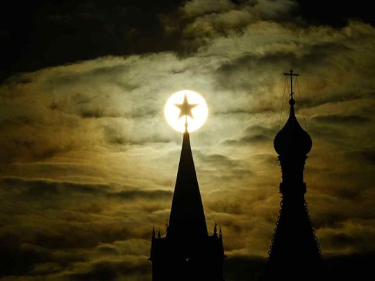 The sun is pictured behind the Kremlin's Spasskaya tower and St. Basil's Cathedral during sunset in downtown Moscow. 