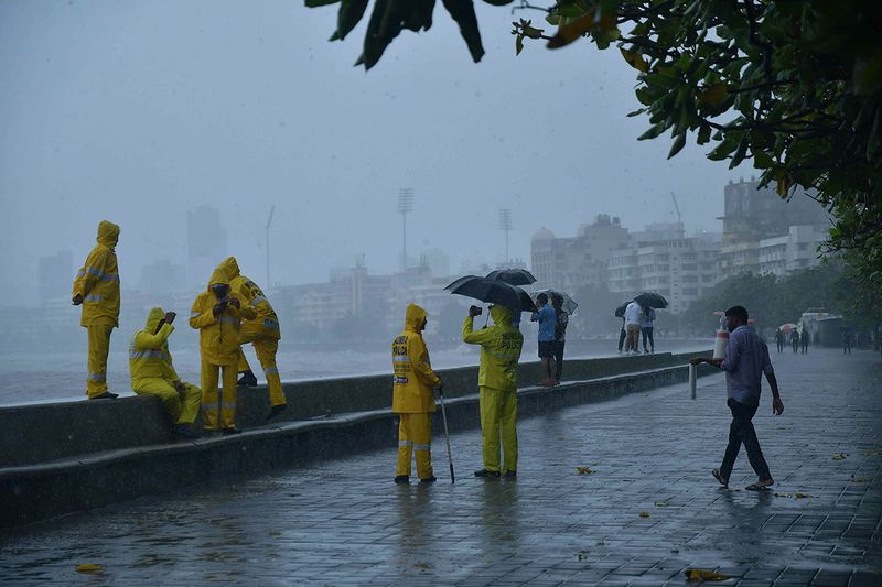  Police personnel stand guard near Marine drive amid heavy rainfall as India Meteorological Department (IMD) issues an Orange alert till July 9 as heavy rain lashes city, in Mumbai on Tuesday.