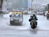 Commuters wade through a waterlogged road amid heavy rainfall, in Mumbai on Tuesday.