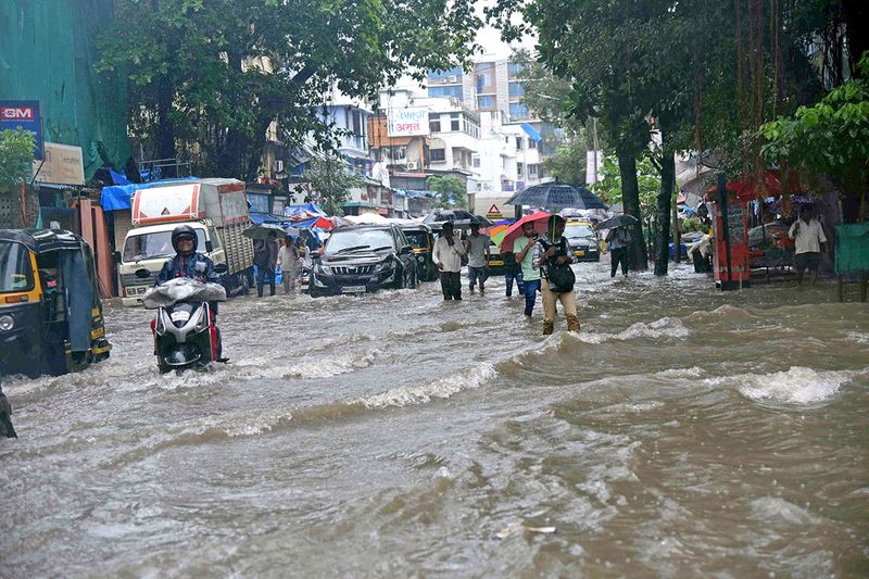 Mumbai, July 05 (ANI): Commuters move through a waterlogged Shraddhanand Road during heavy rainfall, at Vile Parle East, in Mumbai, on Tuesday. (ANI Photo)