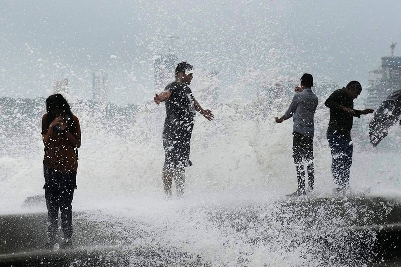 People enjoy high tide waves on the Arabian Sea coast during monsoon rains in Mumbai, India, Wednesday, July 6, 2022. 