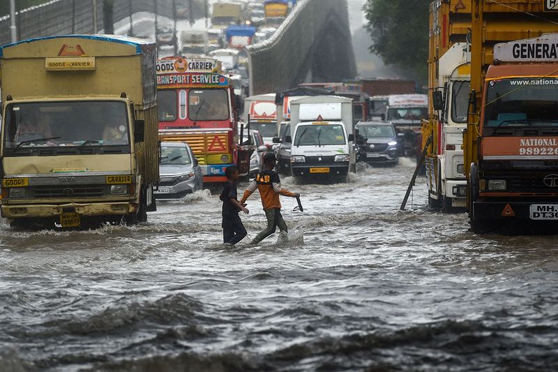 Vehicles drive through flooded street during rain showers in Mumbai on July 5, 2022. 