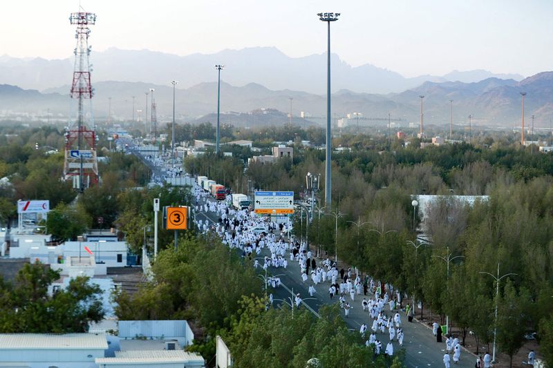 Muslim pilgrims walk toward Mount Arafat, also known as Jabal al-Rahma (Mount of Mercy), to perform their morning prayers,  southeast of the holy city of Mecca, during the climax of the Hajj pilgrimage, early on July 8, 2022.