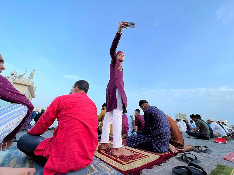 A boy taking a selfie as people gather to perform prayers at Eid Musalla, Sharjah. 