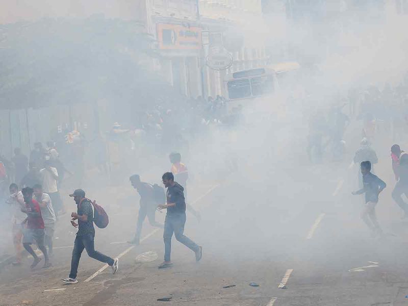 Demonstrators run from tear gas used by police during a protest demanding the resignation of President Gotabaya Rajapaksa, near the president's residence in Colombo, on July 9, 2022.