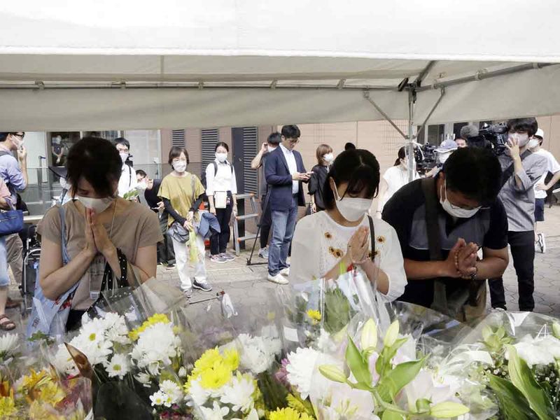 Mourners offer tribute near the crime scene where former Japanese Prime Minister Shinzo Abe was fatally shot during a political event in Nara, Japan, on Saturday, July 9, 2022. 
