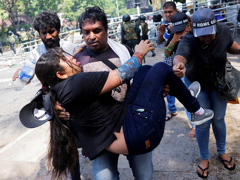 A demonstrator carries an injured woman near President's residence after riot police used tear gas to disperse demonstrators during a protest demanding the resignation of President Gotabaya Rajapaksa.
