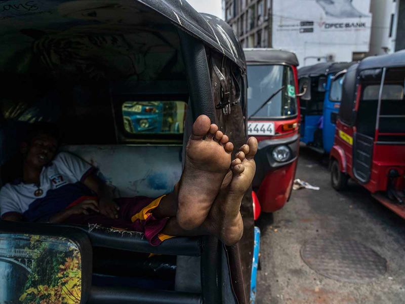 A driver of an autorickshaw sleeps inside his rickshaw while waiting in a queue to buy petrol at a fuel station in Colombo, Sri Lanka, Tuesday, July 12, 2022.