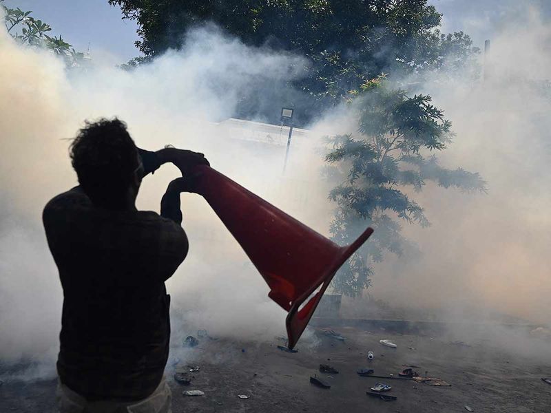 A man throws acone amid tear gas as demonstrators take part in an anti-government protest outside the office of Sri Lanka's prime minister in Colombo on July 13, 2022.