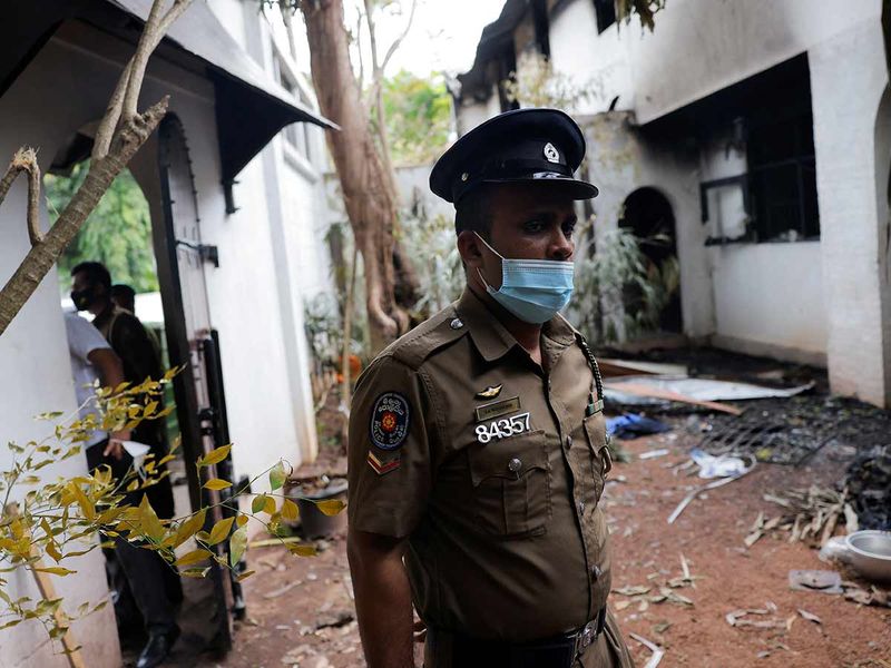 A police officer stands guard near a part of the private residence of the Prime Minister Ranil Wickremesinghe after it was burnt by demonstrators during a protest against him