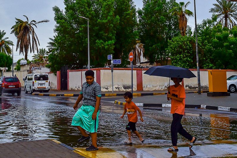 Both residents of Dubai and Sharjah were pleasantly surprised in the afternoon by a gentle drizzle that turned into a cooling shower on Sunday. | Above: A pedestrian uses his umbrella to keep from getting wet in Sharjah.