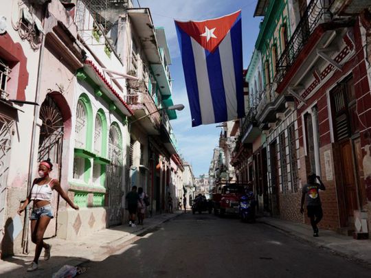 People walk under a Cuban flag hanging in downtown Havana.