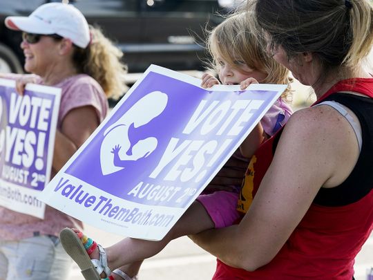 A child holds up a Vote Yes to a Constitutional Amendment on Abortion while being held by her mother along 135th Street on August 01, 2022 in Olathe, Kansas. 