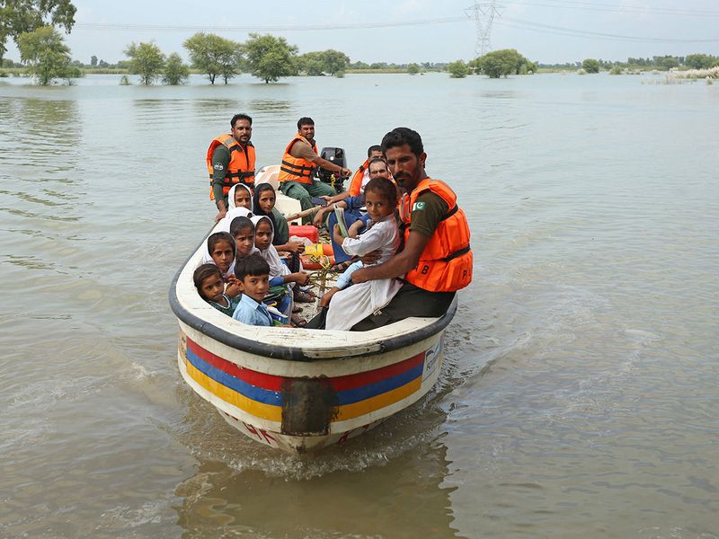 Rescue workers use a boat to drop children back home after school in a flood hit area following heavy monsoon rains in Dera Ghazi Khan district in Punjab.