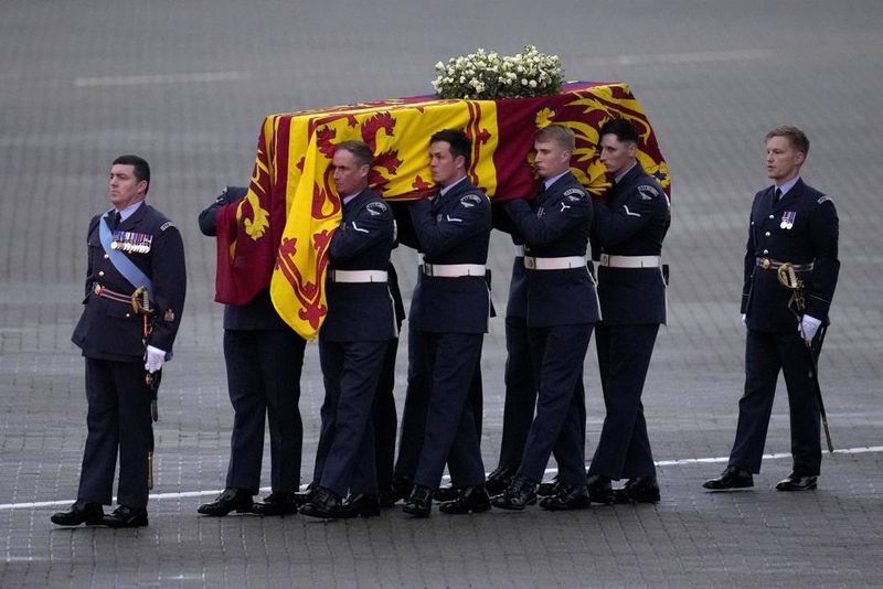 The coffin of Queen Elizabeth II is carried off a plane by the Queen's Colour Squadron at RAF Northolt in London