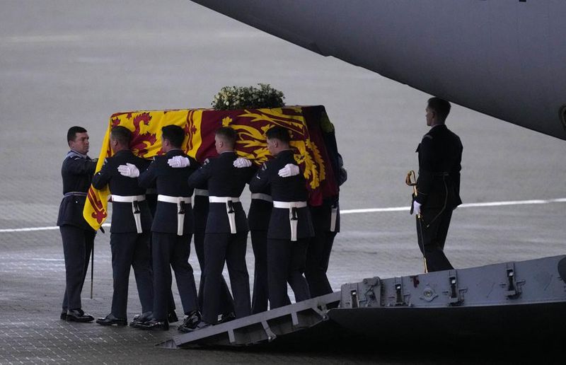 The coffin of Queen Elizabeth II is carried off a plane by the Queen's Colour Squadron at RAF