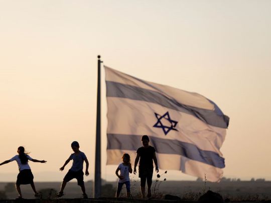Israeli kids play next to an Israeli flag next to the Israeli Syrian border at 