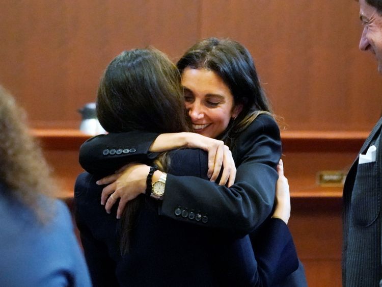 Attorney Joelle Rich hugs attorney Camille Vasquez, as attorney Ben Chew looks on, at the end of the daily proceedings at the Fairfax County Circuit Courthouse in Fairfax, Va., U.S., May 16, 2022. Steve Helber/Pool via REUTERS