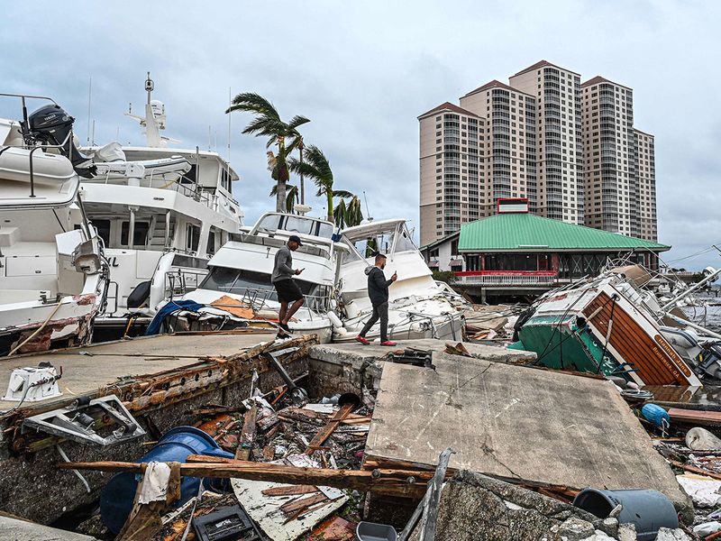 Residents inspect damage to a marina as boats are partially submerged in the aftermath of Hurricane Ian in Fort Myers, Florida, on September 29, 2022. 