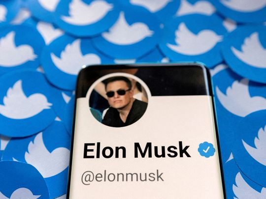 Elon Musk's Twitter profile is seen on a smartphone placed on printed Twitter logos in this picture illustration