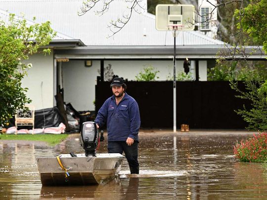 Australia flood A man pushes a boat as floodwaters inundate a Victorian residential