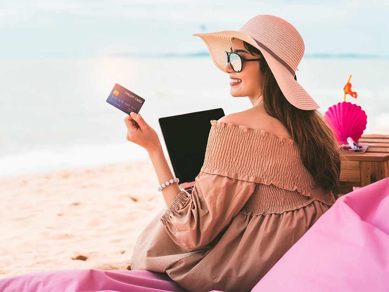 Tourist woman at beach holding a credit card