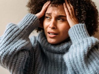 Woman in a blue sweater holding her head