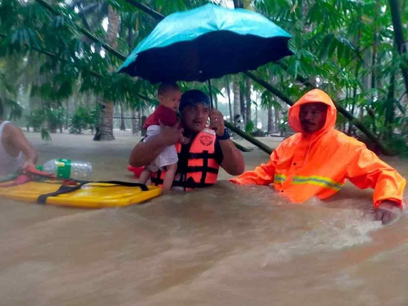 A Philippine Coast Guard (PCG) rescuer carries a child following flooding due to Tropical Storm Nalgae, in Hilongos, Leyte, Philippines. 