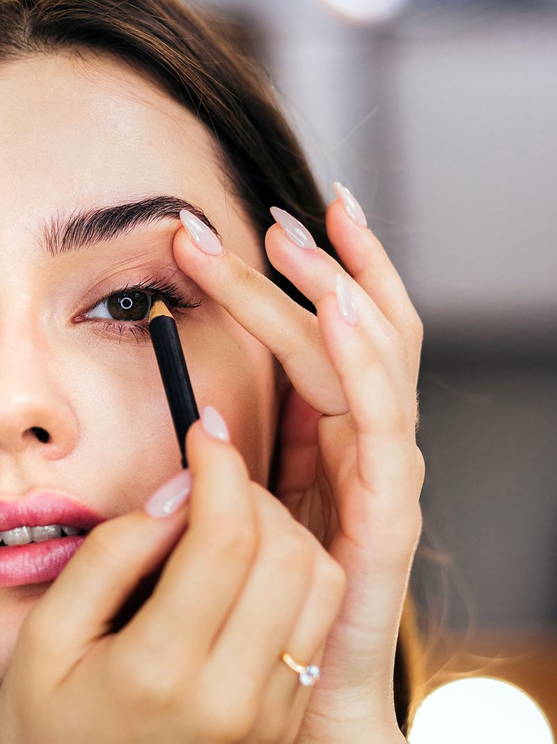 A woman applying black eyeliner