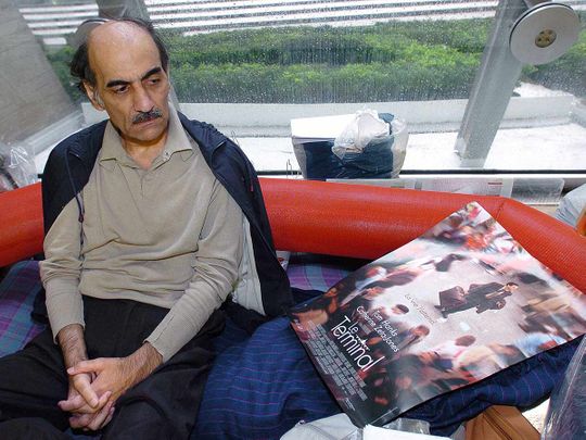 In this file photo taken on August 12, 2004 Mehran Karimi Nasseri looks at a poster of the movie inspired by his life, in the terminal 1 of Paris Charles De Gaulle airport.