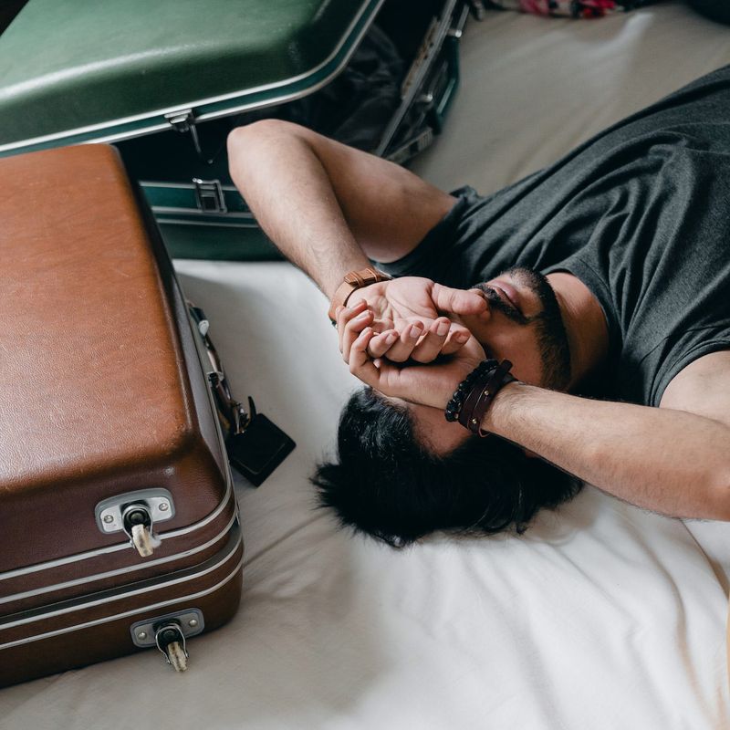A man who is asleep beside suitcases 