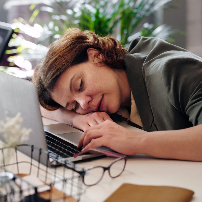 A woman taking a nap on her desk at work