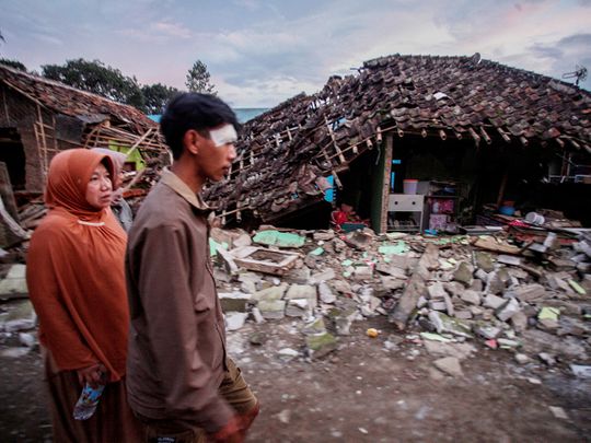 Locals walk past collapsed houses, after earthquake hit in Cianjur, West Java