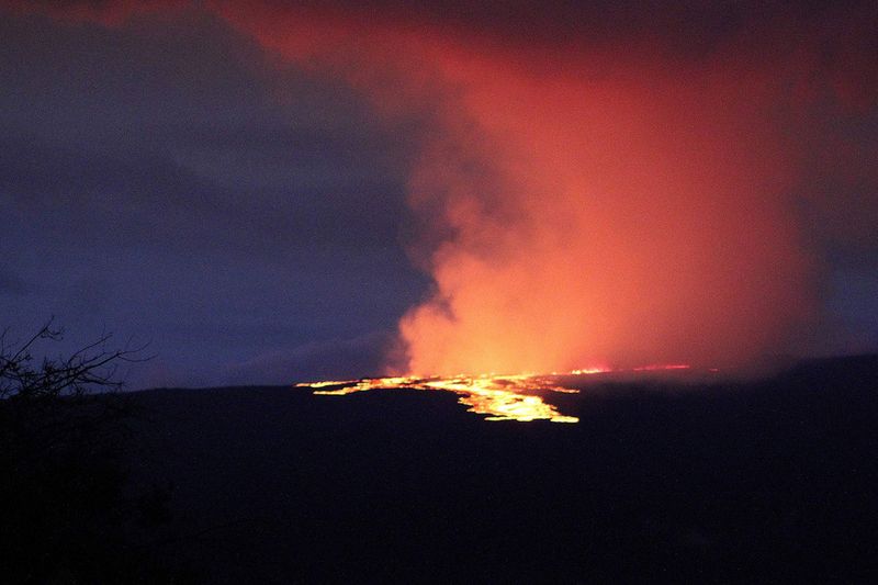 Lava pours out of the summit crater of Mauna Loa about 6:35 a.m. Monday, Nov. 28, 2022, as seen from Gilbert Kahele Recreation Area on Maunakea, Hawaii. Mauna Loa, the world’s largest active volcano,  began spewing ash and debris from its summit, prompting civil defense officials to warn residents on Monday to prepare in case the eruption causes lava to flow toward communities. 