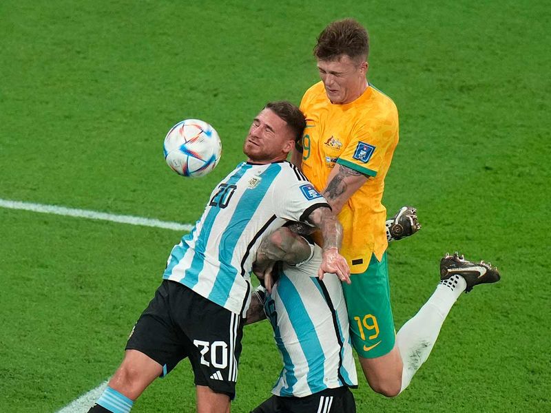 Argentina's Alexis Mac Allister goes for the header with his teammate Nicolas Otamendi and Australia's Harry Souttar during the Qatar World Cup round of 16 at the Ahmad Bin Ali Stadium in Doha, on  Saturday, Dec. 3, 2022. 