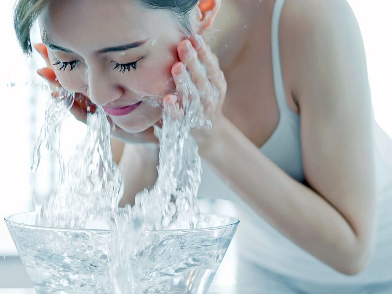 A woman washing her face with water 