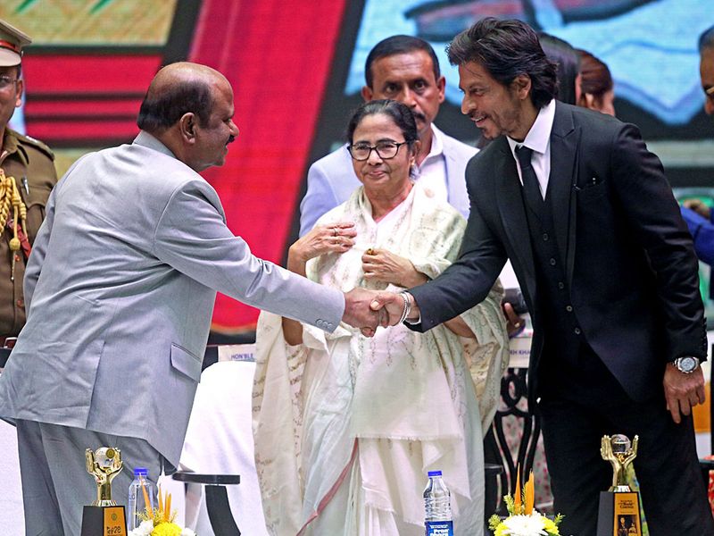 West Bengal Governor C.V. Ananda Bose interacts with Bollywood actor Shah Rukh Khan during the inaugural programme of the 28th Kolkata International Film Festival, as the State Chief Minister Mamata Banerjee looks on, in Kolkata on Thursday.